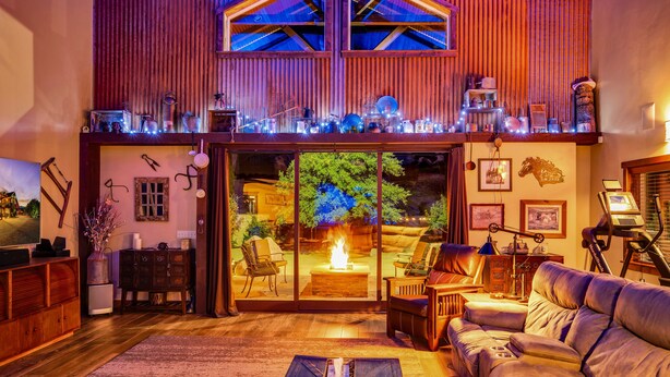 A cozy living room with a fireplace, comfortable seating, and a large window overlooking a garden.