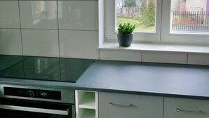 A kitchen with white cabinets, a black stove, and a window with a view of a house and trees.