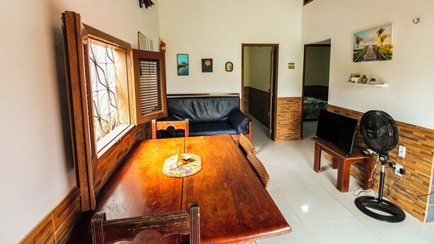 Un coin repas avec une table en bois, des chaises, un canapé bleu et un ventilateur.