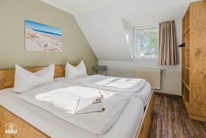 Un dormitorio con dos camas, una ventana con cortinas, un radiador y un armario de madera.