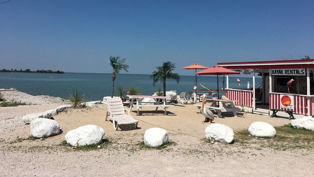 A beachside area with lounge chairs, a kayak rental kiosk, and a view of the sea. - Sarah Cottage - 226 Cottage Road, Steeprock , Manitoba (Grahamdale)