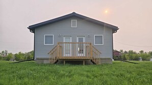 A single-story house with a front deck, a small porch, and a single door. - Sarah Cottage - 226 Cottage Road, Steeprock , Manitoba (Grahamdale)