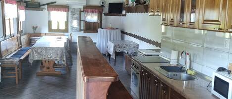 A spacious kitchen with wooden cabinets, a central island, and a dining area with a long table and benches.