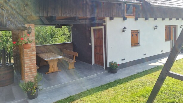 Une maison de campagne avec un banc en bois et des plantes en pot.