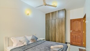 Ein Schlafzimmer mit einem Bett, einem Deckenventilator, einem Kleiderschrank und einer Tür.