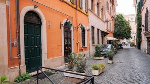 A narrow cobblestone street lined with buildings, a green door, and potted plants. - TrasteverHome -Cisterna Secrets at the Heart of Trastevere (Rome)