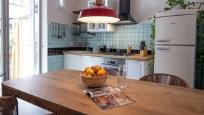 A kitchen with a wooden table, a bowl of fruit, a water bottle, and a magazine. - TrasteverHome -Cisterna Secrets at the Heart of Trastevere (Rome)