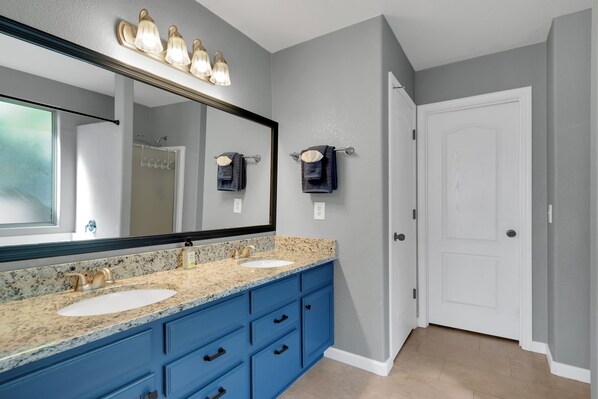 A bathroom with two sinks, a large mirror, and a towel rack.