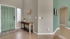 A hallway with a green door, a wooden console table with a plant, and a wall-mounted picture. - Beautiful 4-bedroom house with Pool in Tucson (Tucson)
