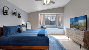 A bedroom with a bed, a ceiling fan, a window with curtains, a dresser, and a TV. - Beautiful 4-bedroom house with Pool in Tucson (Tucson)