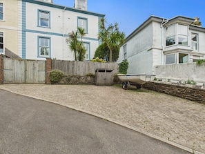Un quartier résidentiel avec une allée pavée, une clôture en bois, un petit bateau et un mur de pierres.