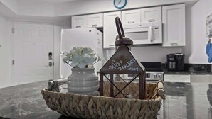 A kitchen counter with a woven basket containing a white vase with flowers and a metal lantern with "Sandy Beaches #404" written on it. - Hot Tub, Oceanfront, Heated Pools, King, Cable TV, W/D (Orange Beach)