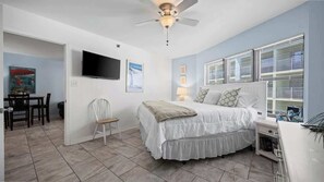 A bedroom with a bed, a desk, a chair, a TV, and a window with blinds. - Hot Tub•Oceanfront •Heated Pools•King•Cable TV•W/D (Orange Beach)
