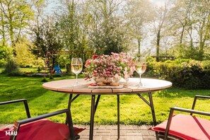 An outdoor dining table with a floral centerpiece, two glasses of white wine, and a basket of bread. - Holiday Farm Mau - House 6 (Fehmarn)