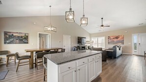 A spacious living area with a large island, dining table, and seating.