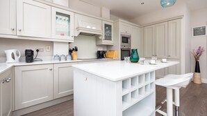 Una cocina moderna con armarios blancos, una isla central y taburetes de bar.
