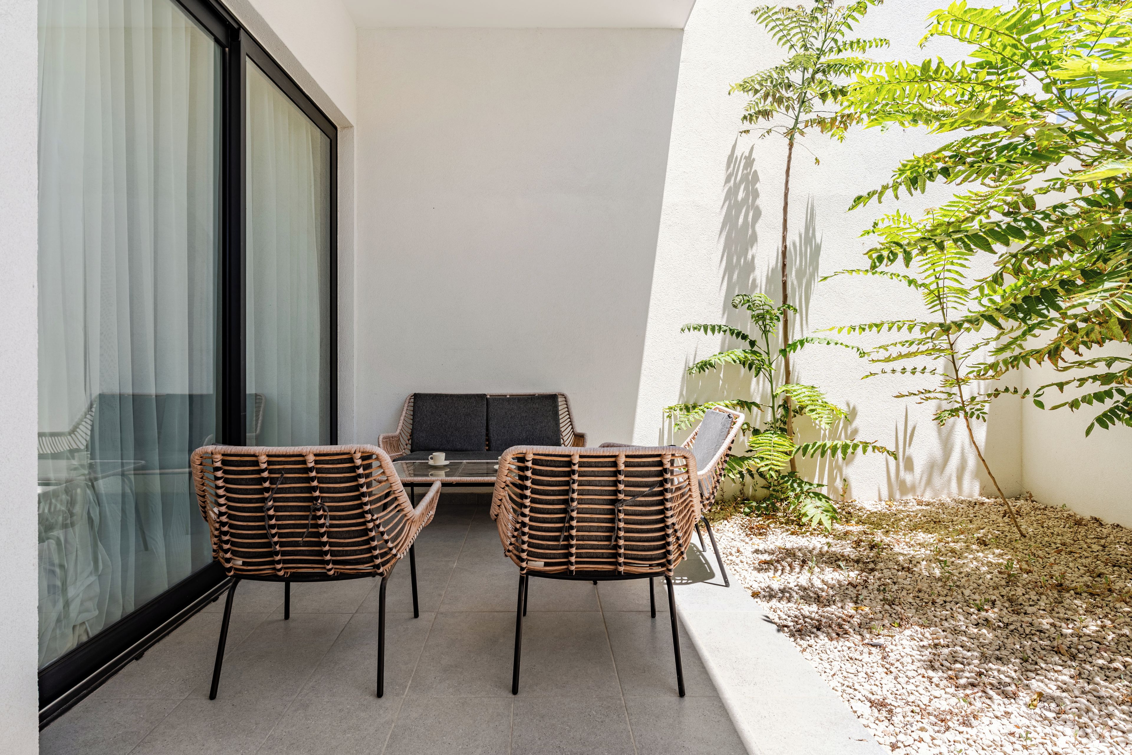 A balcony with two wicker chairs, a small table, and a sofa.