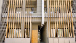 Un edificio moderno con una entrada central flanqueada por listones verticales de madera y barras de metal.
