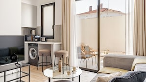 Un apartamento moderno con cocina, comedor y balcón con muebles de mimbre.