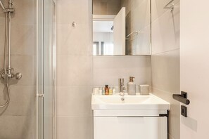 Un bagno moderno con box doccia in vetro, lavandino bianco con articoli da toilette e specchio sopra il lavandino.