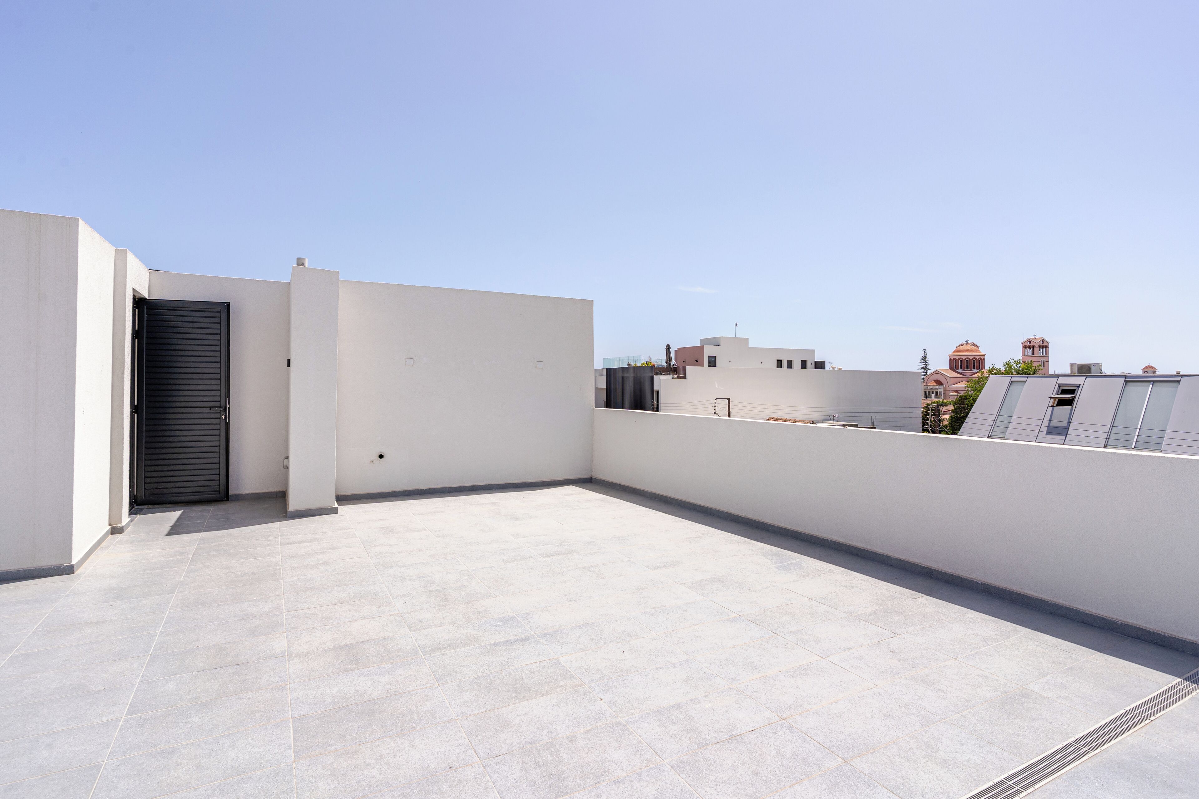 Eine Dachterrasse mit flachem, gefliestem Boden und einer geschlossenen Tür.