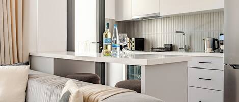 A modern kitchen with a central island, a dining area with a sofa, and a view through a window.