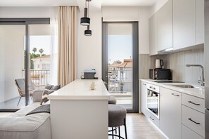 Een moderne keuken met een centraal eiland, een zithoek met een bank en stoelen, en een stadszicht door het raam.