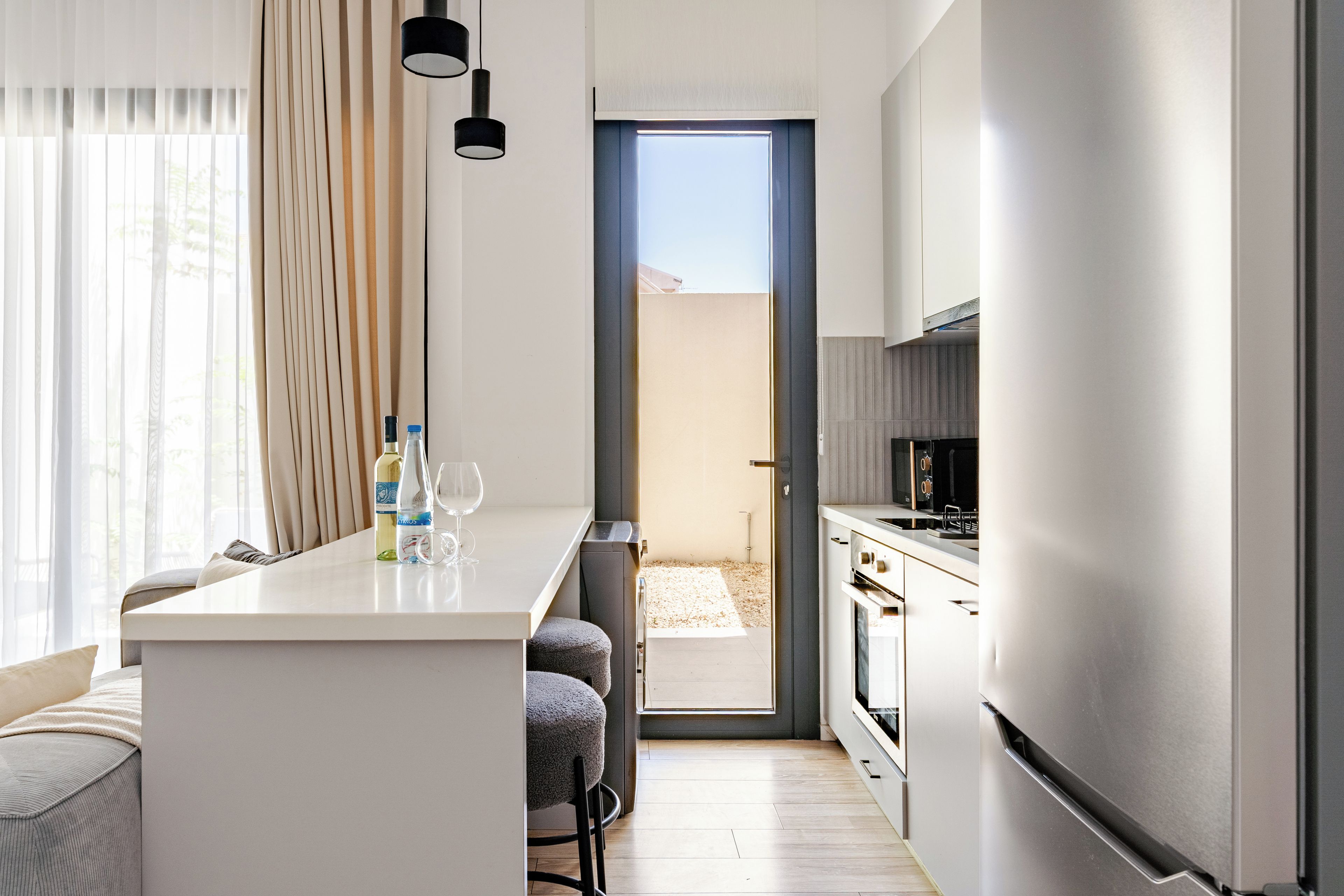 Cocina moderna con una isla central, zona de comedor con sofá y vista a un edificio.