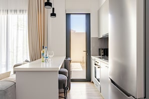Een moderne keuken met een centraal eiland, een zithoek met een bank, en uitzicht op een gebouw.