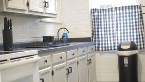 A kitchen with white cabinets, a black trash bin, and a patterned rug. - Modern Luxury 1BR Prime Location by Oakley, Rookwood, Downtown & Top Hospitals (Norwood)