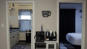 A compact kitchen with a coffee machine, a small refrigerator, and a window with checkered curtains. - Modern Luxury 1BR Prime Location by Oakley, Rookwood, Downtown & Top Hospitals (Norwood)