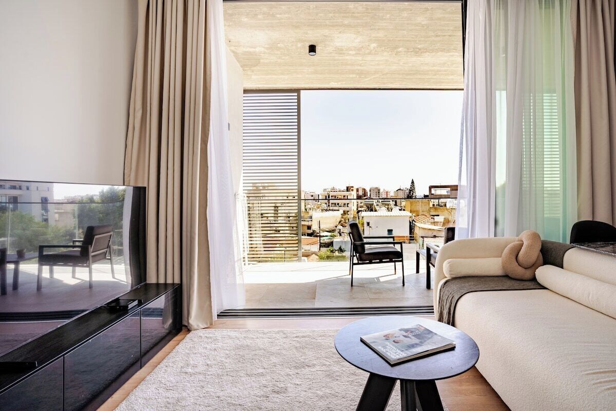 Ein modernes Wohnzimmer mit einer Couch, einem Couchtisch, einem Fernseher und einem Balkon mit Blick auf die Stadt.