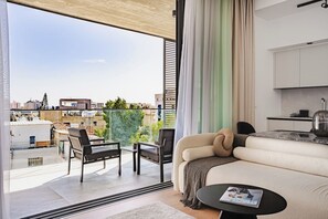 Eine moderne Wohnung mit Balkon, einer Couch, einem Esstisch und einer Küchenzeile.