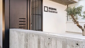 A building entrance with a metal gate, a concrete barrier, and a sign for Sequoia Residence. - Yamas Urban Living Sequoia Residence (Limassol)