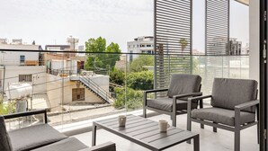 A modern balcony with two grey armchairs, a small table, and two white mugs. - Yamas Urban Living Sequoia Residence (Limassol)