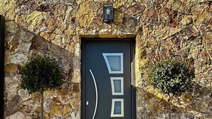 Una entrada con pared de piedra y una puerta moderna con diseños geométricos.