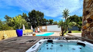 Un jacuzzi en una terraza de madera, con una piscina al fondo.