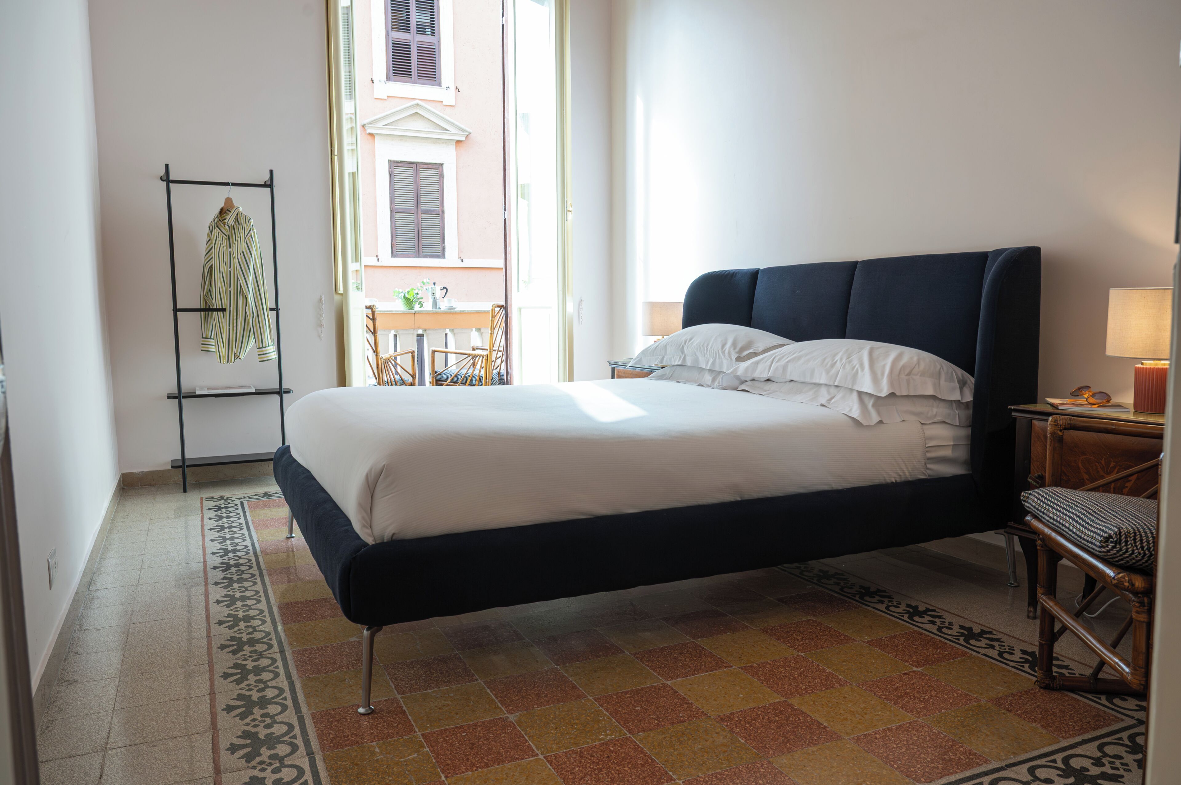 Una camera da letto con un letto, un comodino, una sedia, una finestra e vista sull'esterno.