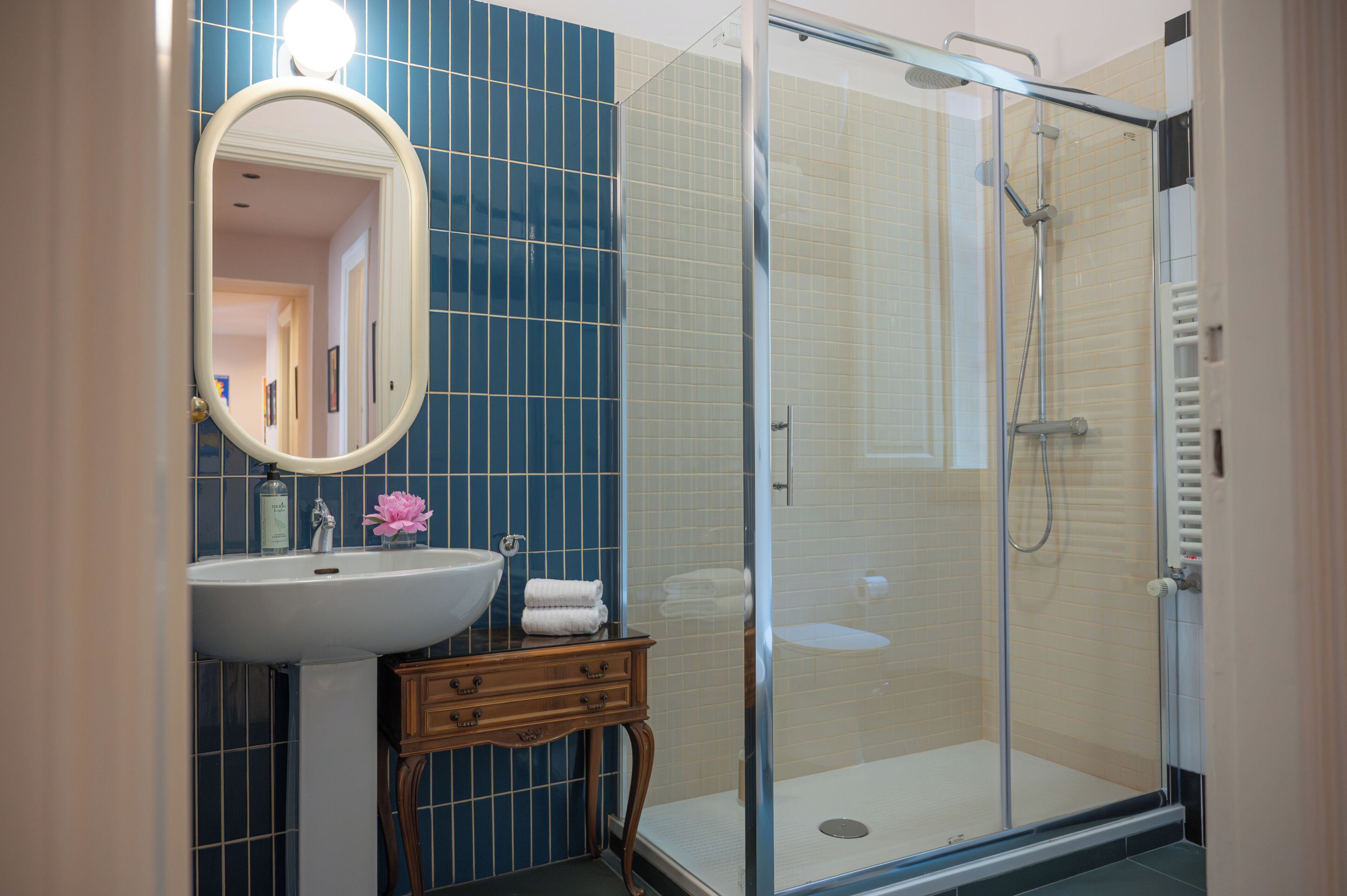 A bathroom with a sink, mirror, vanity, and a glass-enclosed shower.
