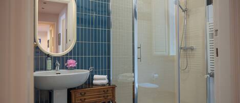 A bathroom with a sink, mirror, vanity, and a glass-enclosed shower.