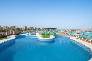 Una piscina al aire libre, sombrillas, tumbonas