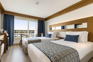 A hotel room with two beds, a desk, and a balcony with a railing. - Nile Cruise Fantasy every Friday from Aswan 3 nights and every Monday from Luxor 4 nights (Aswan)