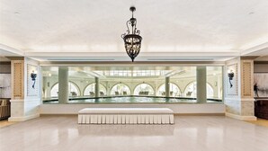 Een ruime lobby met een groot zwembad, een decoratieve kroonluchter en een bank.