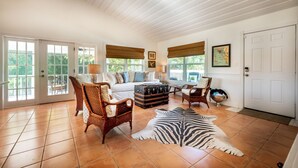 A spacious living room with a white sofa, wicker chairs, a zebra rug, and a wooden coffee table.