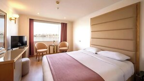 Habitación de hotel con cama, escritorio, silla, televisión y ventana con vista.