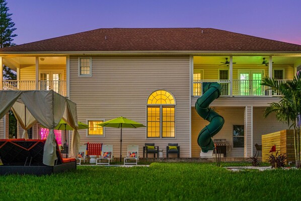 A two-story house with a covered patio, outdoor seating, and a slide. - 21 Guest Retreat•2StorySlide•Golf Sim•HtdPool (Largo)