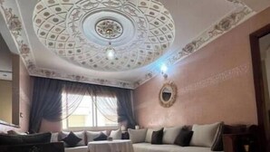 Een woonkamer met een gedessineerd plafond, een bank, een bijzettafeltje en een kast.