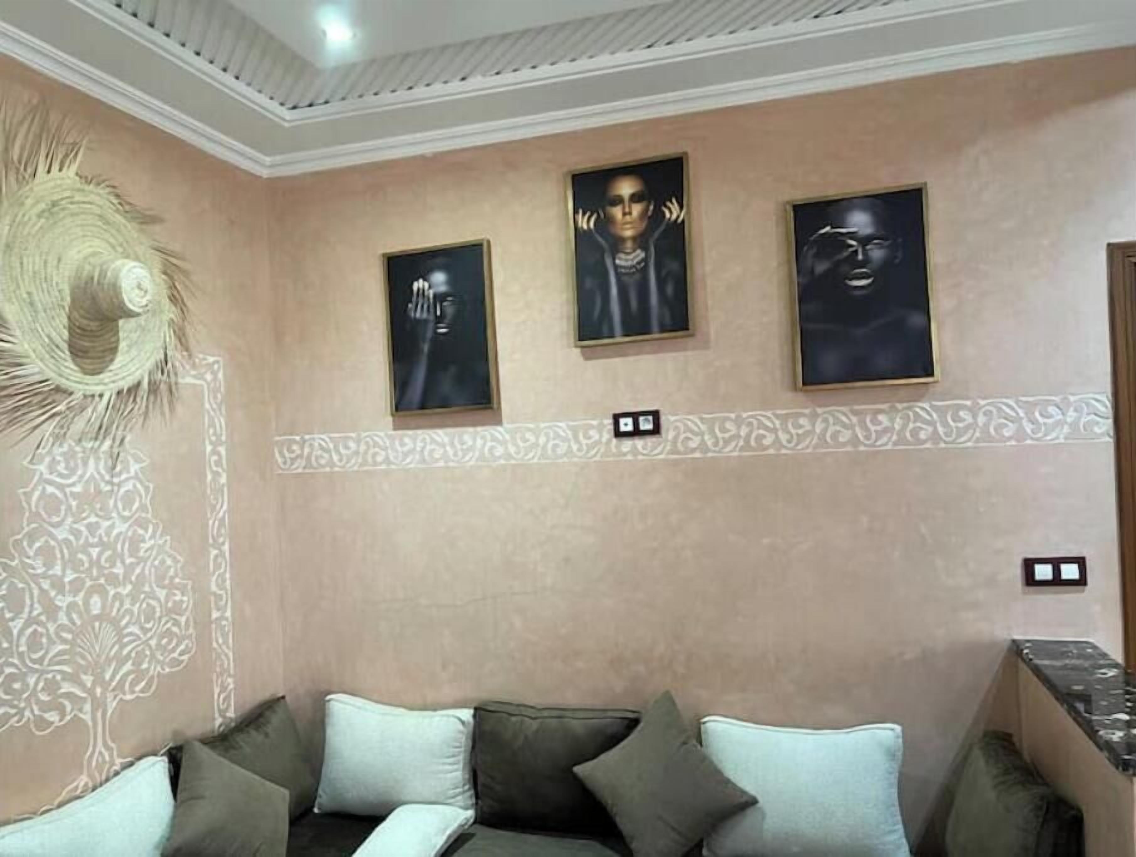 Una habitación con pared color beige, un panel decorativo en la pared, un tapiz tejido y un sofá con cojines.