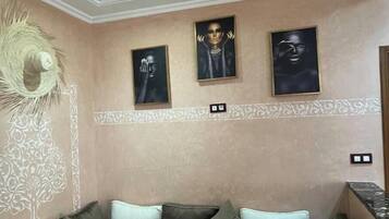 Una habitación con pared color beige, un panel decorativo en la pared, un tapiz tejido y un sofá con cojines.
