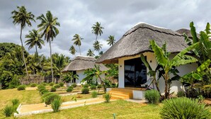 Um resort com chalés de telhado de palha, cercado por vegetação exuberante e palmeiras.